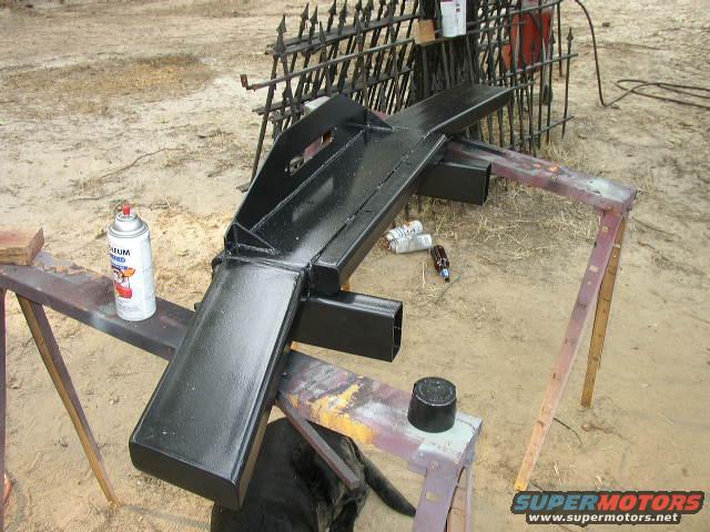 Black metal bumper on sawhorses, spray paint can nearby