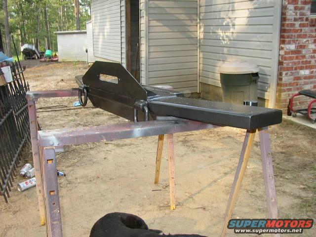 Black custom bumper on sawhorses outside a building