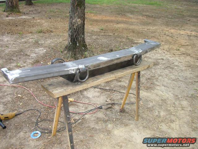 Custom steel bumper with two D-ring tow hooks, resting on sawhorses outdoors