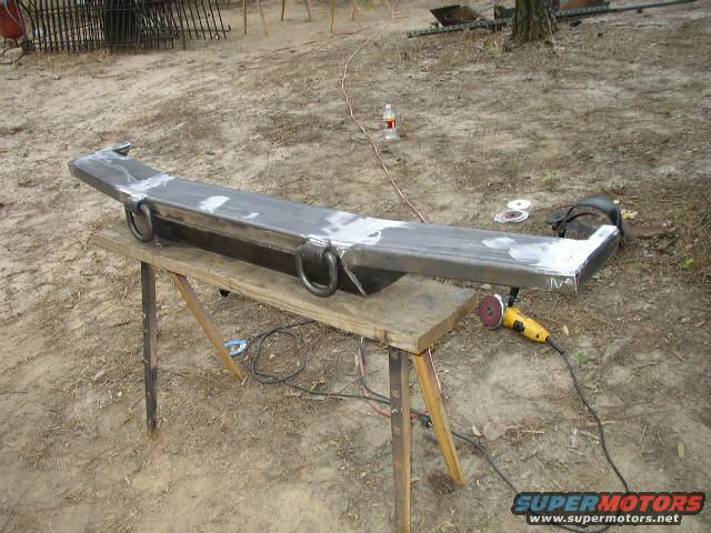 Custom metal bumper with D-rings on a workbench, with a grinder nearby