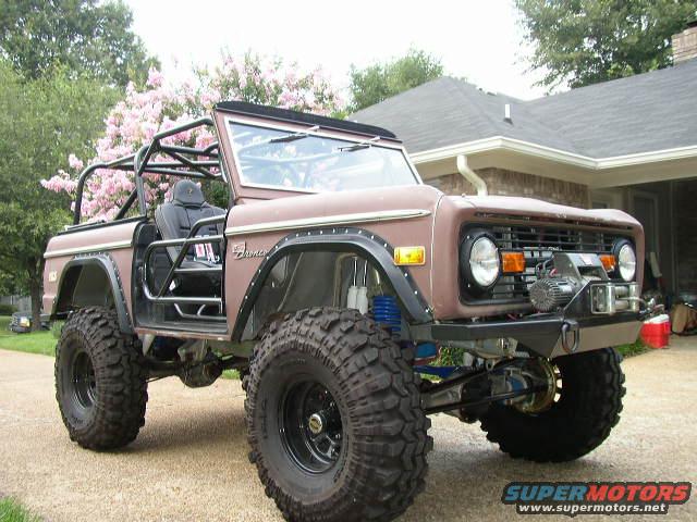 Brown Ford Bronco with roll cage, large tires, and a winch on the front bumper