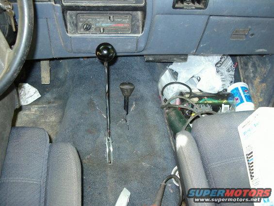 Vehicle interior with floor shifter, dashboard, and passenger seat cluttered with items