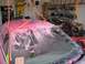1994 Ford Probe - A car is being worked on in a garage, covered in pink dust with a drawing on the windshield.