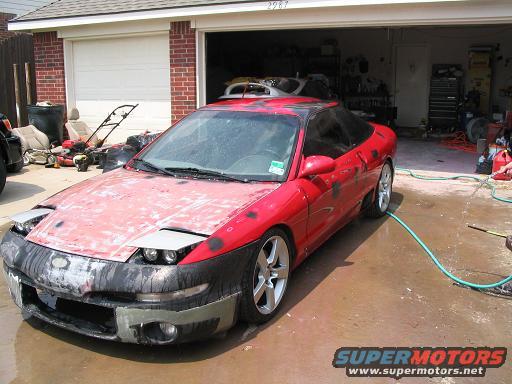 Red 1994 Ford Probe with pop-up headlights, undergoing repairs