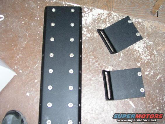 Black metal console with multiple screw holes and two L-shaped brackets with screw holes
