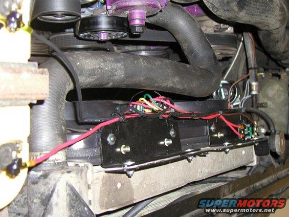 Engine bay wiring for an electric fan, showing a black mounting bracket with red and green wires connected to a relay