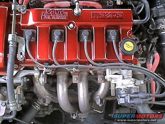 Red Mazda engine valve cover with "16 VALVE DOHC" and "Mazda" text, close-up view