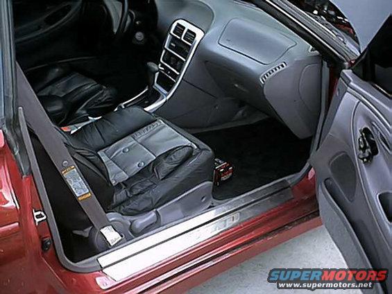 Interior view of a car showing the driver's seat, dashboard, and center console. A seatbelt is visible