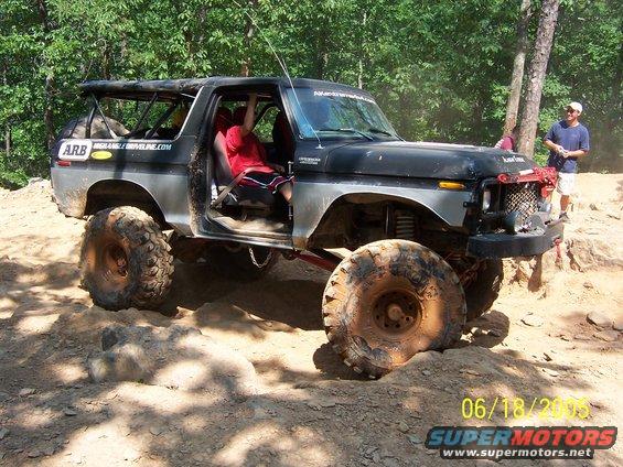 Black and silver 1978 Ford Bronco with large off-road tires on a dirt trail