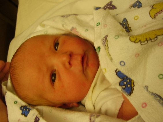 Baby wrapped in a blanket with cartoon dinosaurs