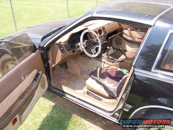 1984 Nissan 300ZX interior with brown upholstery, aftermarket steering wheel, and camouflage seat cover