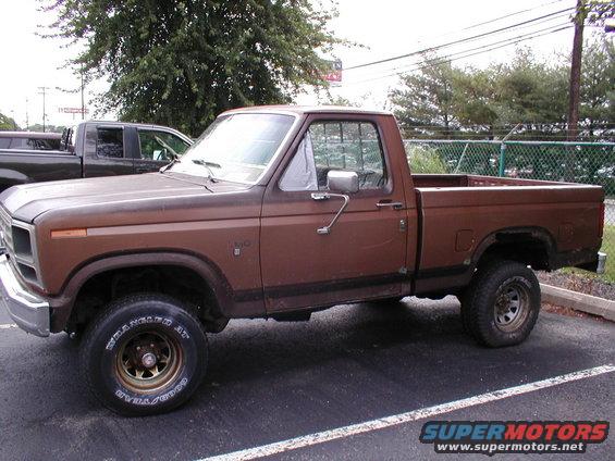 Brown pickup truck parked, with another dark pickup truck behind it