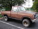 1979 Ford Bronco - This brown pickup truck is parked in a lot with trees in the background.