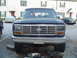 1982 Ford Bronco - Front view of a dark blue Ford Bronco, a prominent chrome grille and rectangular headlights.