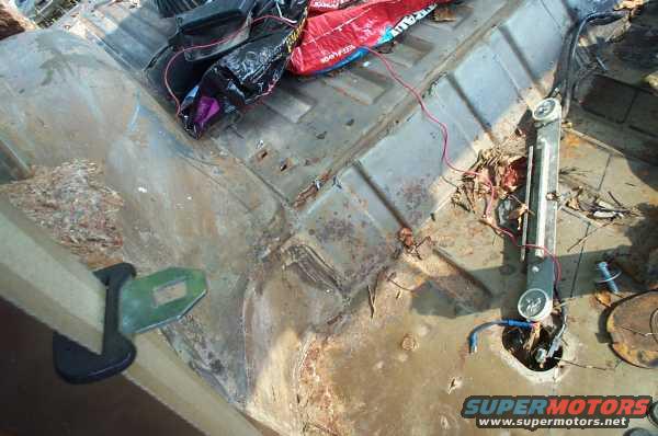 Interior of a rusty vehicle with debris and wiring visible