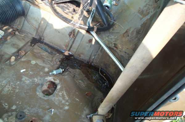 Interior floor of a vehicle showing rust and water damage