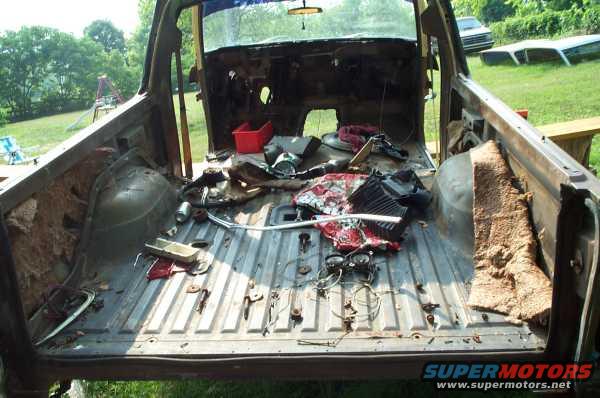 Back of a stripped-down vehicle with parts scattered in the bed