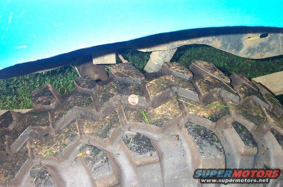 Muddy off-road tire with a coin on tread