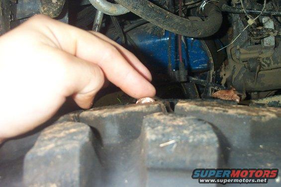 Close-up of a nail in a tire tread, with a hand pointing to it