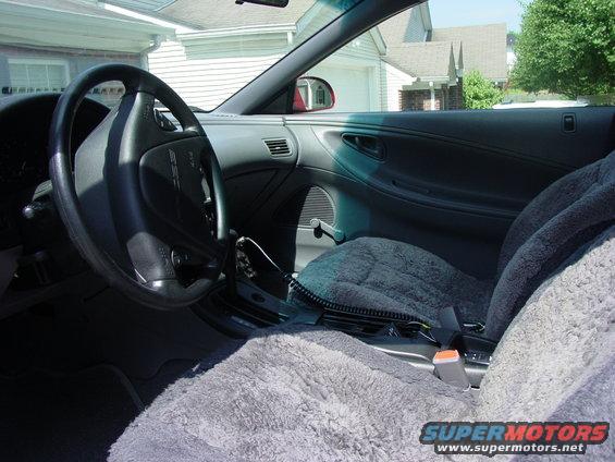 Interior view of car with fuzzy grey seat covers and steering wheel