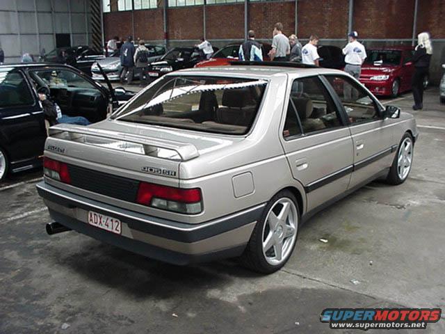 Silver Peugeot 405 sedan with custom wheels and a rear spoiler. License plate ADX-412