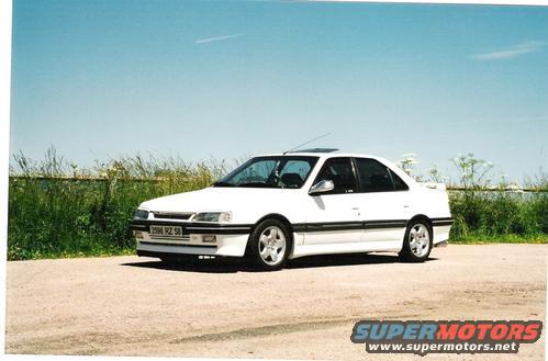 White 1989 Peugeot 405 sedan parked on a dirt lot, viewed from the front three-quarter angle