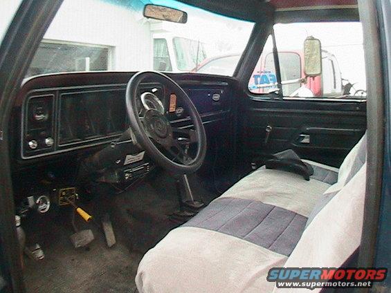 View of a truck's interior, showing the dashboard, steering wheel, and seats. A "SUPERMOTORS" watermark is visible