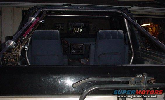 Interior view of vehicle with roll cage and dark blue seats. 'ALTO' visible on rear window