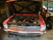 1966 Chevrolet Nova - The front of a red 1966 Chevrolet Nova is shown with its hood raised, revealing the engine compartment.