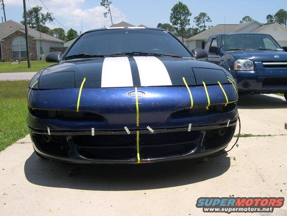1997 Ford Probe front end with blue paint, white racing stripes, and yellow tape on the bumper