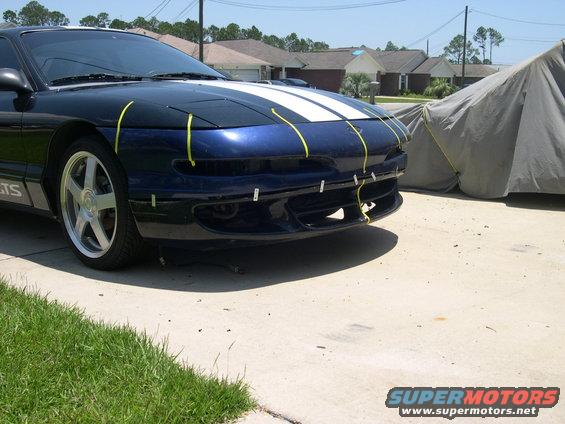 Blue 1997 Ford Probe with white racing stripes and yellow tape on the front bumper