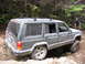 2000 Jeep Cherokee - Jeep Cherokee navigating a challenging rocky trail with a person observing.
