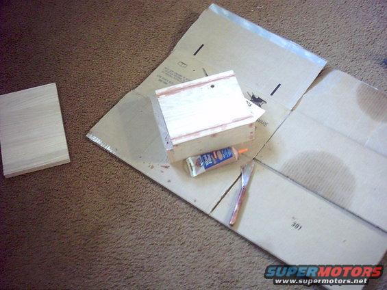Wood pieces, tube of glue, and a knife on cardboard