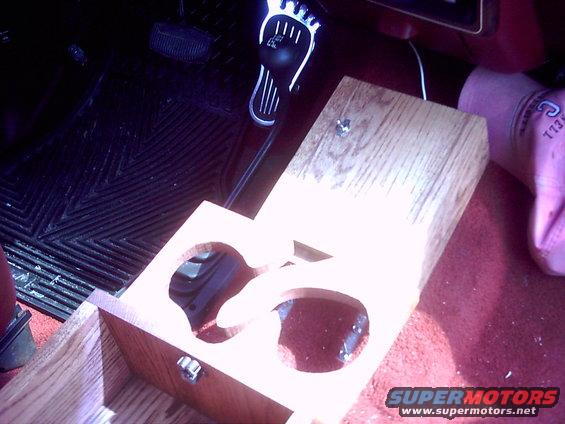 Wooden cup holder installed on vehicle floor near pedals