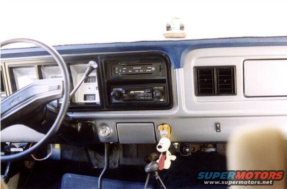 Interior shot of a truck dashboard with steering wheel, radio, and vents. A Snoopy-like keychain hangs from the dash