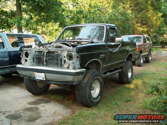 Black Ford Bronco with hood open, parked next to another SUV