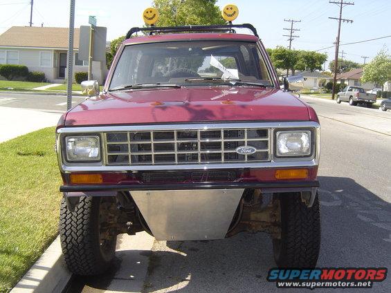 Maroon Ford Bronco II with aftermarket skid plate and smiley face lights on roof rack