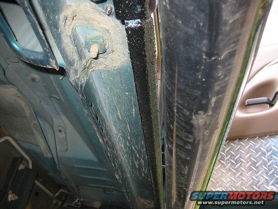Underside of a vehicle showing the door sill and frame, with some dirt and grime