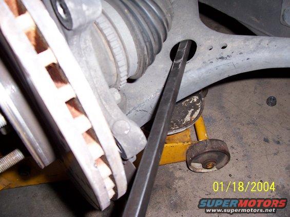 Close-up of a car's suspension component being worked on with a pry bar. Date stamp 01/18/2004