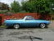 1970 Ford Ranchero - Side profile of a blue 1970 Ford Ranchero with a wooden fence and trees in the background.