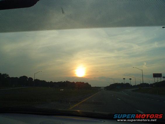 Highway scene with sun setting on the left, viewed from inside a vehicle