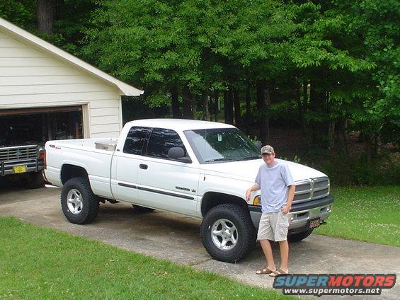 Guy standing next to a white Dodge Ram pickup truck parked in a driveway