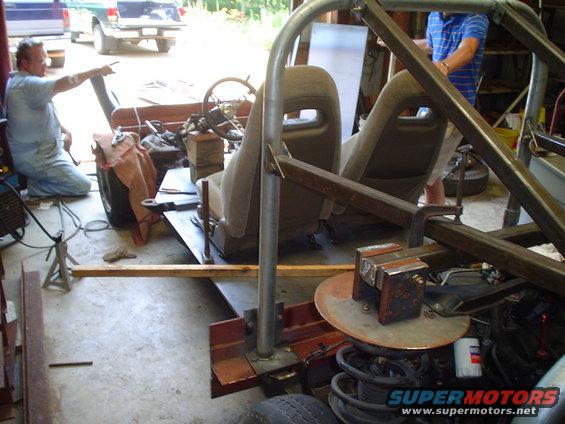 Custom off-road vehicle build in progress with roll cage, bucket seats, and steering wheel visible