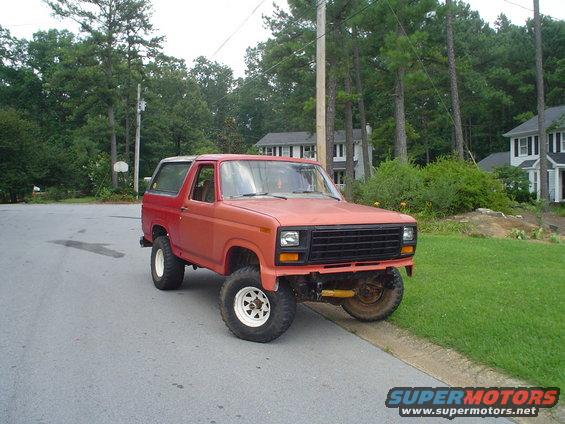 Red SUV with a black grille and white-rimmed wheels parked on a residential street