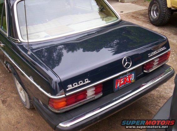 Dark blue Mercedes-Benz sedan rear view, showing '300D' and 'Turbo Diesel' badges. Another vehicle is partially visible to the right