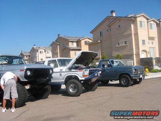 Three pickup trucks parked on a street, one with hood open. The truck on the right appears to be a 1979 Ford F-150