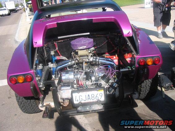 Purple custom car with exposed V8 engine, off-road tires, and a California license plate reading 4GJA869