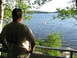 1986 Ford Bronco - A man stands on a porch, gazing out at a tranquil lake surrounded by lush greenery.