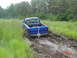1995 Dodge 1500 - A blue 1995 Dodge 1500 pickup truck is stuck in a muddy trail surrounded by tall grass and trees.