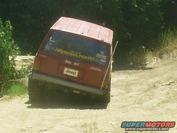Red Jeep Cherokee XJ on dirt road, tilted